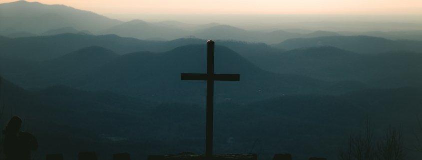 silhouette of cross on top of building during sunset